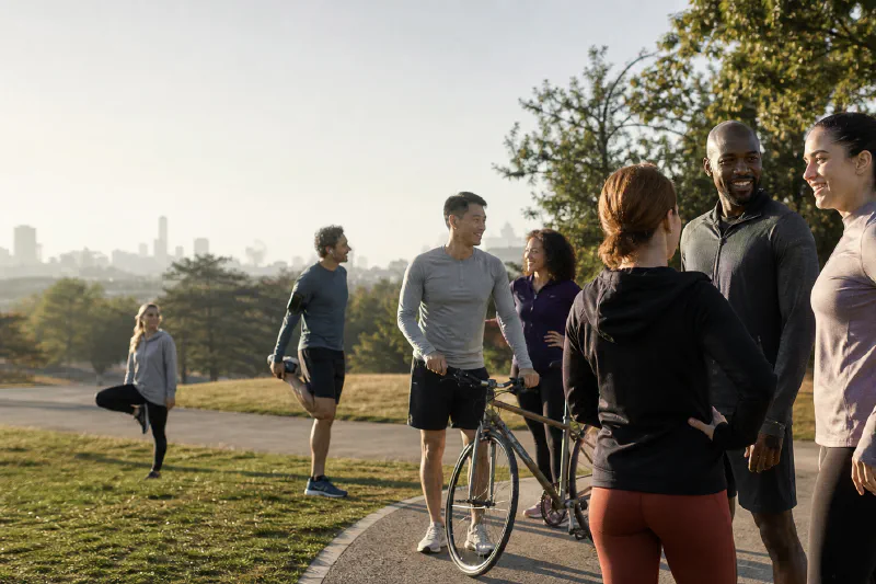Un grupo diverso de adultos se reúne para hacer deporte de forma informal en un parque urbano
